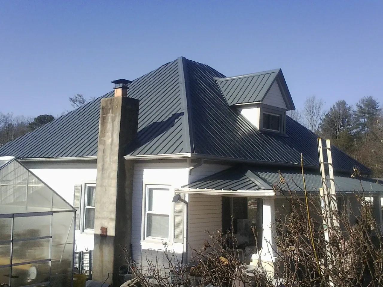 Dark blue standing seam metal roof on a white farmhouse with dormer — Slate & Tile Roof Repair by Roofing Brothers in Pekin