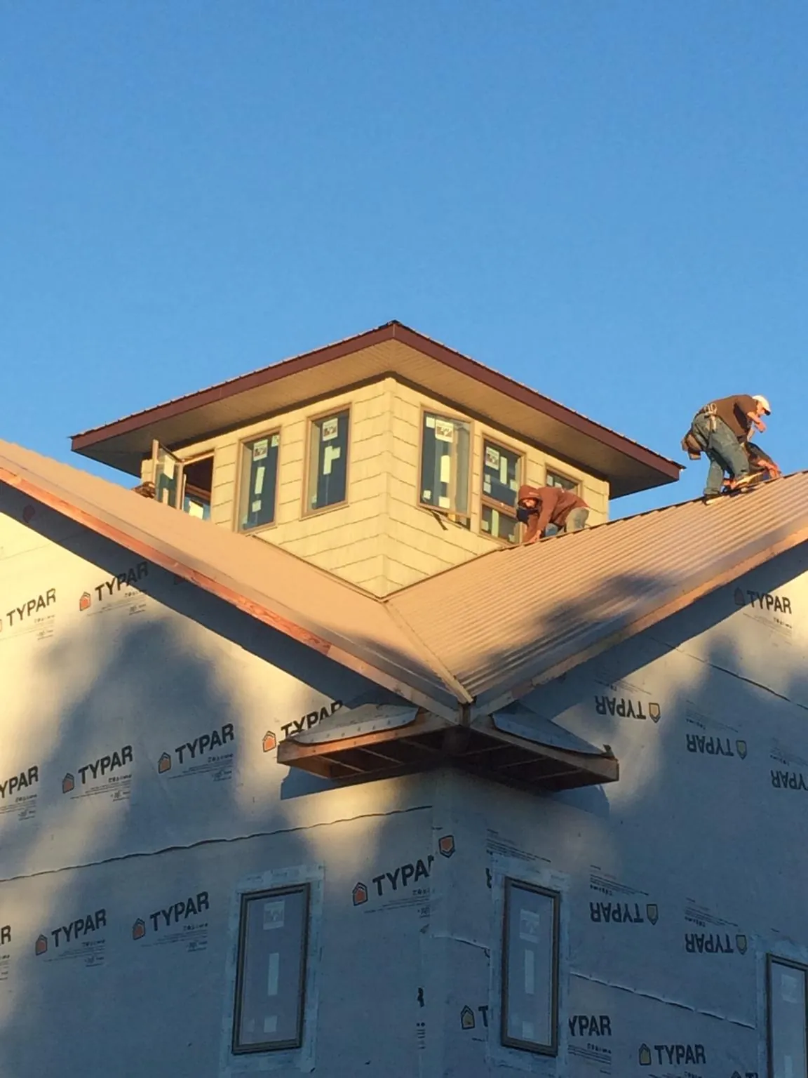 Roofers working around a rooftop cupola on a new metal roof at sunset — Roof Waterproofing in Pekin by Roofing Brothers